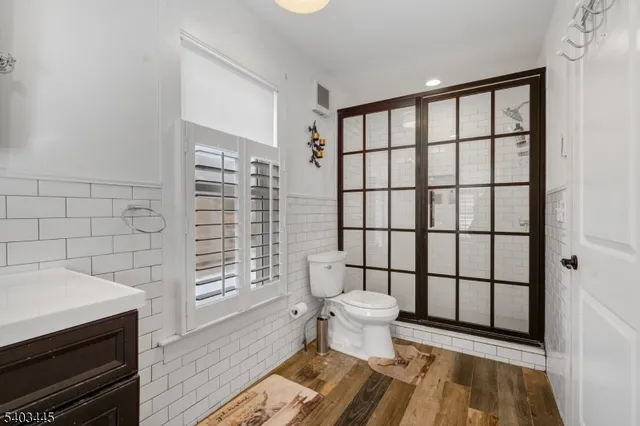 a bathroom with a toilet a sink a mirror and shower