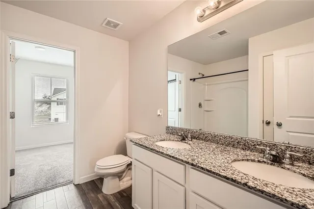 a bathroom with a granite countertop sink toilet a mirror and shower
