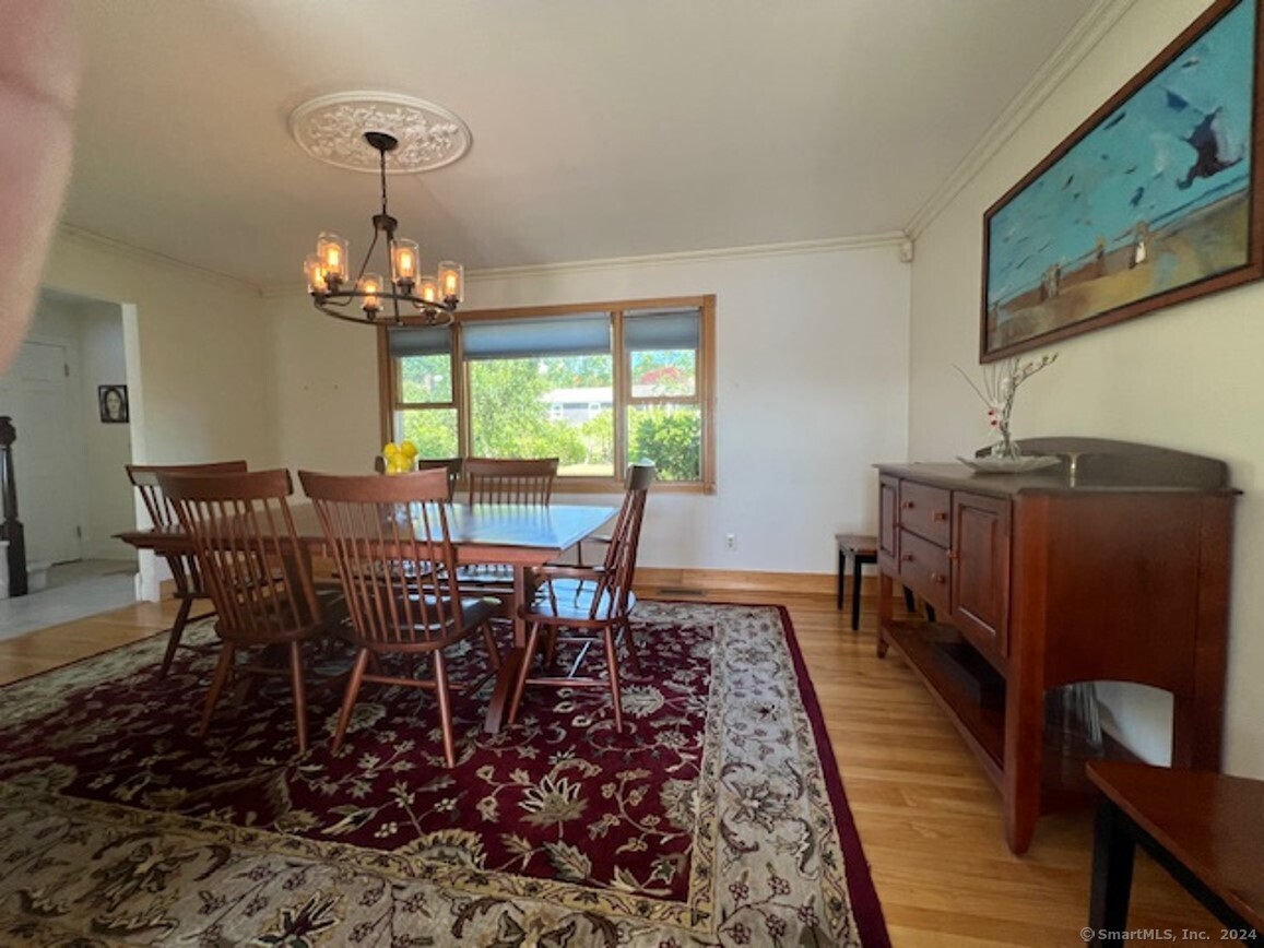 123 Seneca Drive Groton, CT 06340 - Photo 13 of 25 a view of a dining room with furniture a chandelier and wooden floor