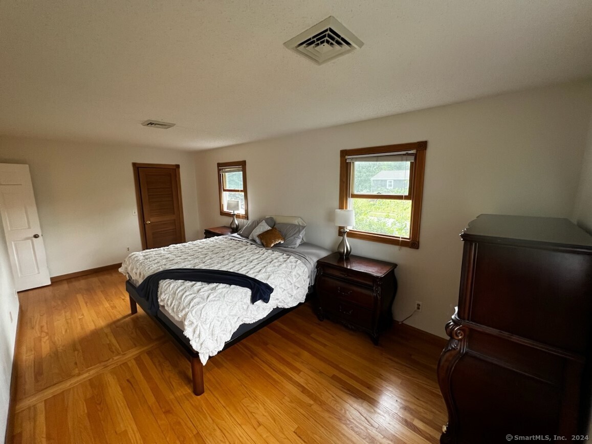 123 Seneca Drive Groton, CT 06340 - Photo 10 of 25 a bedroom with a bed and wooden floor