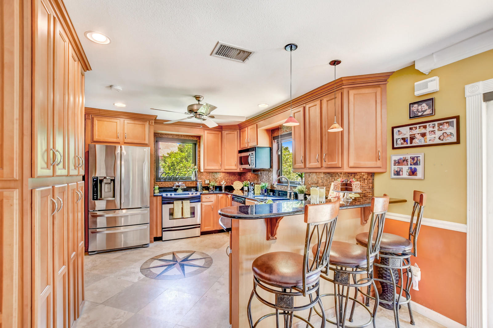 4542 Avalon Street Boca Raton, FL 33428 - Photo 14 of 51 a kitchen with stainless steel appliances granite countertop a refrigerator a stove top oven a dining table and chairs with wooden floor