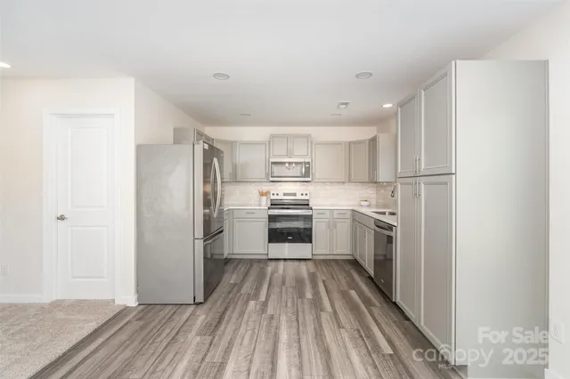 a kitchen with white cabinets stainless steel appliances and a refrigerator