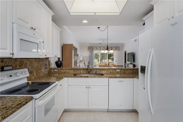 a kitchen with granite countertop white cabinets and white appliances