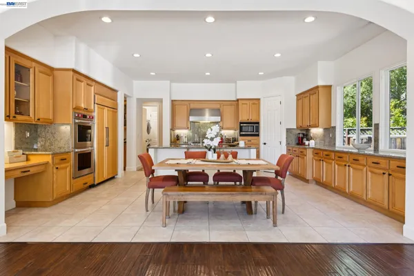 a living room with stainless steel appliances furniture a rug kitchen view and a large window