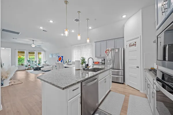 a kitchen with stainless steel appliances granite countertop a stove a refrigerator a sink a dining table and chairs with wooden floor