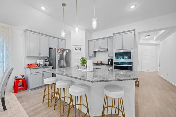 a kitchen with stainless steel appliances granite countertop a kitchen island hardwood floor and a refrigerator