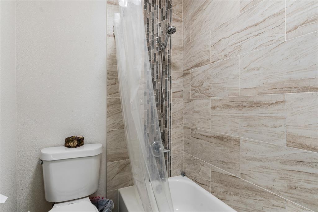 11311 Audelia Road, Unit 102 Dallas, TX 75243 - Photo 19 of 31 Bathtub with shower fixture, full-height tile surround, and mosaic tile accent