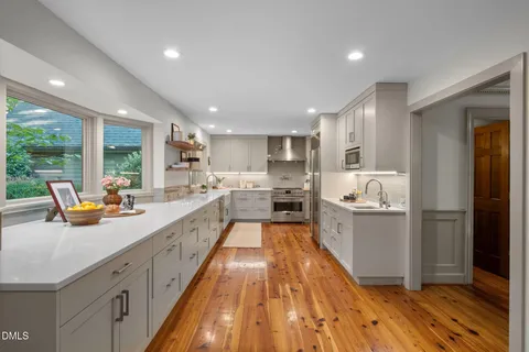 a large white kitchen with lots of counter space a sink and stainless steel appliances