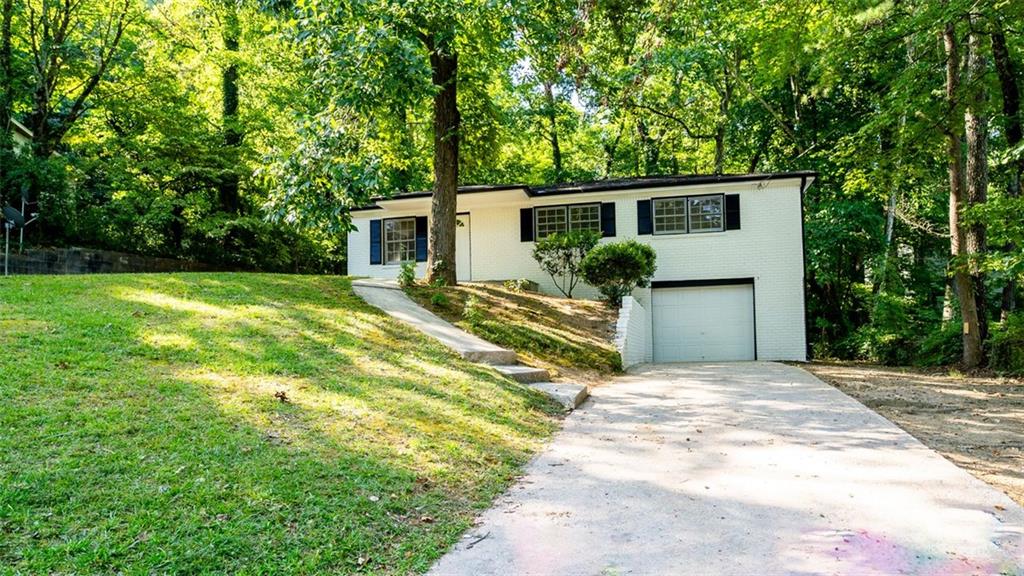 a front view of house with yard and trees in the background