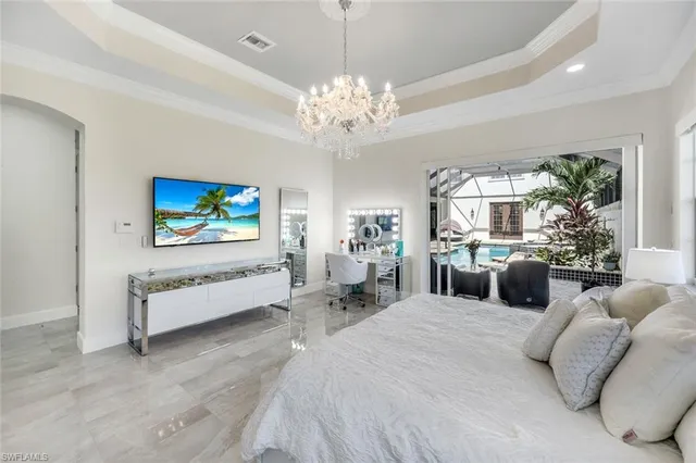 a bedroom with a bed chandelier and window