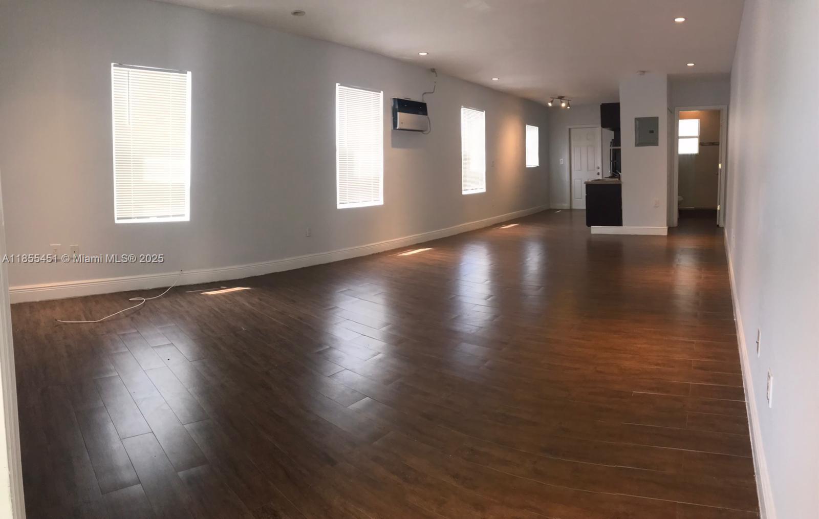 131 Northwest 15th Street, Unit U Miami, FL 33136 - Photo 4 of 6 an empty room with wooden floor and windows