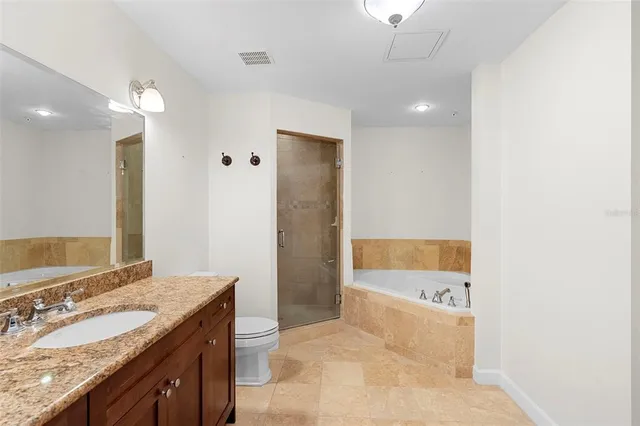 a spacious bathroom with a granite countertop sink a toilet a large mirror and shower