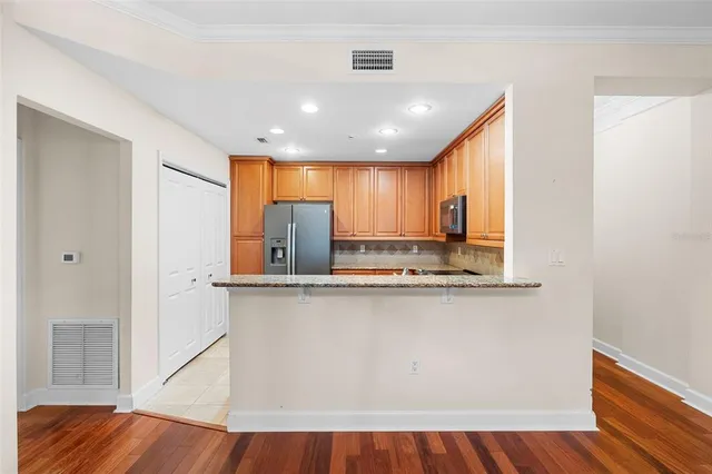 a kitchen with stainless steel appliances granite countertop a refrigerator a sink dishwasher a stove and white countertops with wooden floor