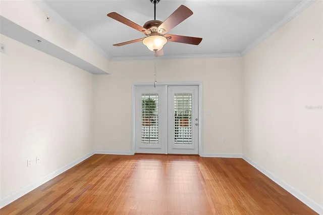 an empty room with wooden floor chandelier fan and windows