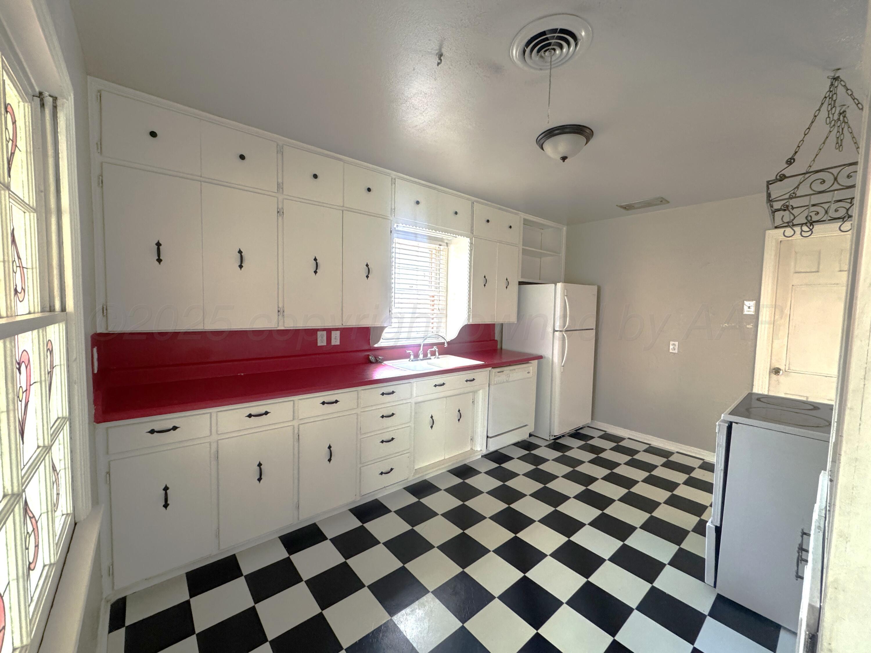 1222 South Bryan Street Amarillo, TX 79102 - Photo 8 of 18 a room with a black white checkered floor with a gaming machine and wooden floor