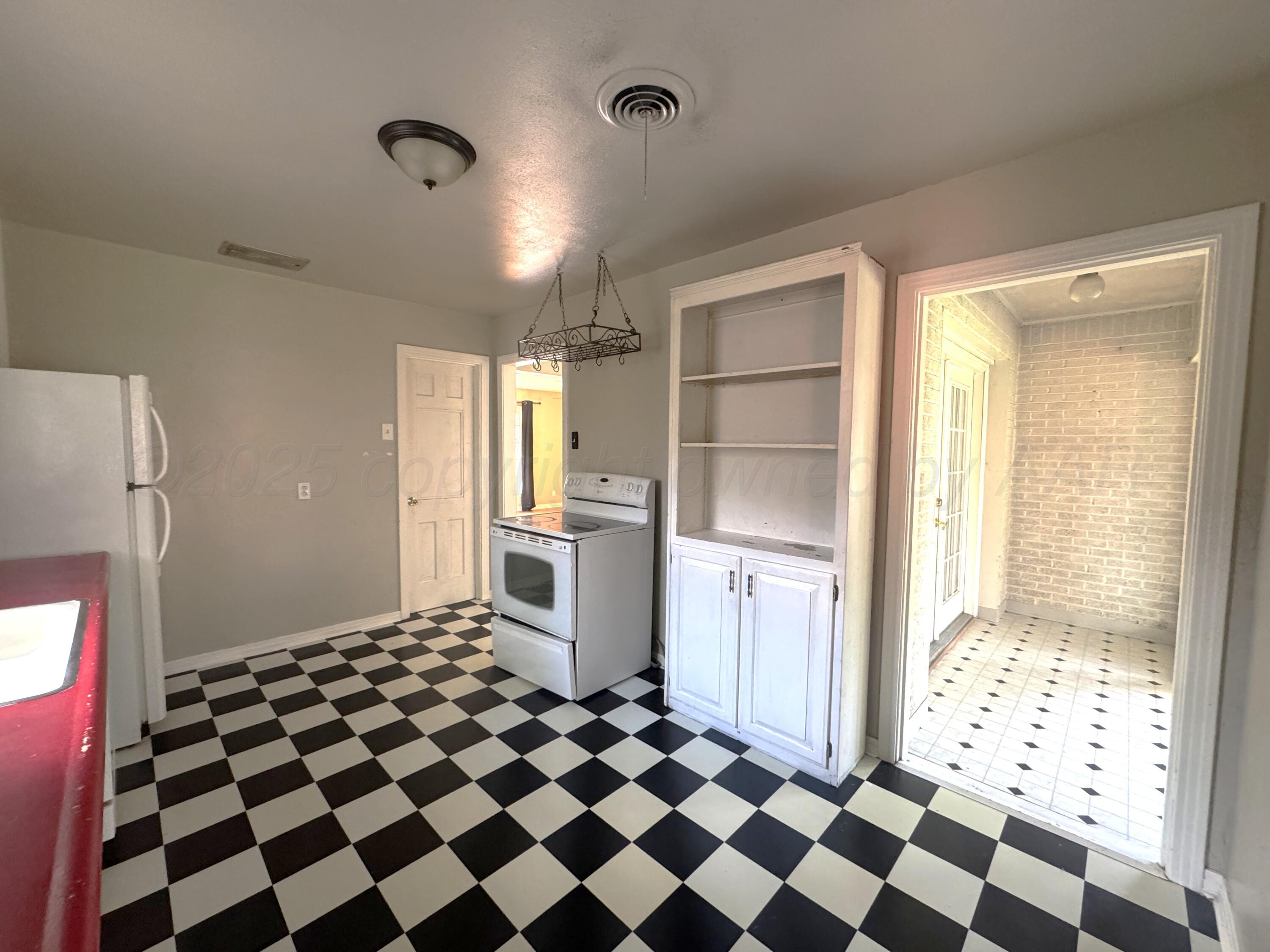 1222 South Bryan Street Amarillo, TX 79102 - Photo 9 of 18 a kitchen with a checkered floor and white cabinets