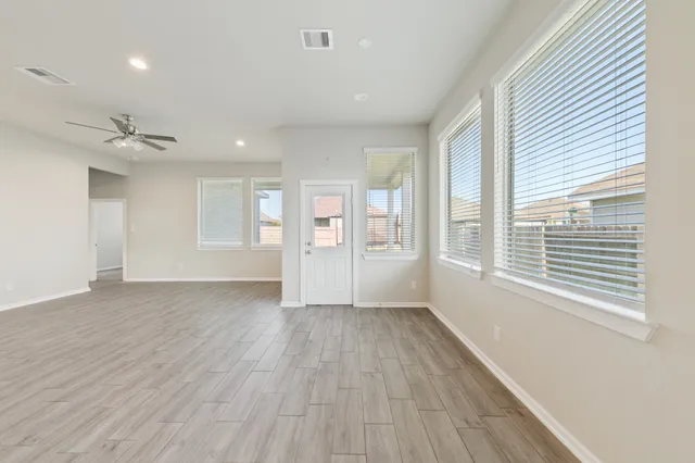 a view of an empty room with a window and wooden floor