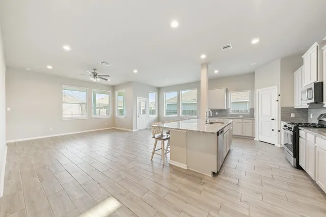 a large white kitchen with lots of counter space a sink and appliances
