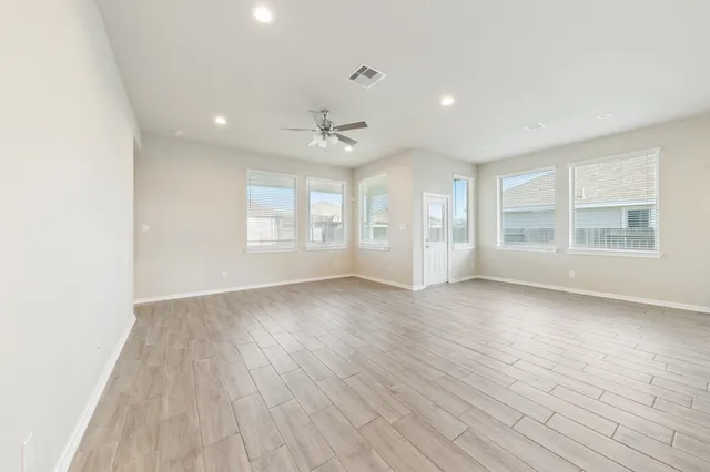 an empty room with wooden floor and windows