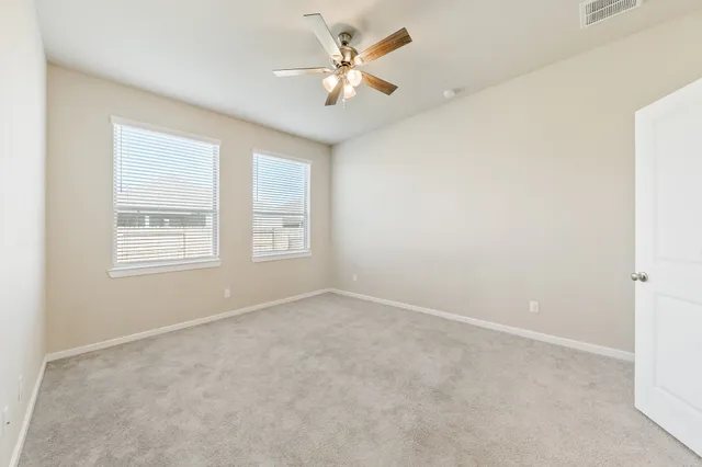 an empty room with windows and ceiling fan