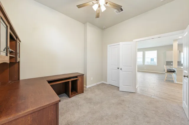 an empty room with windows and fan