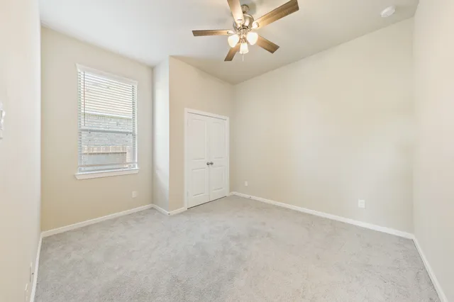 a view of an empty room and chandelier fan