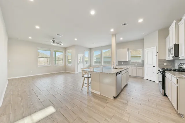 a large kitchen with stainless steel appliances granite countertop a large stove a sink and a refrigerator