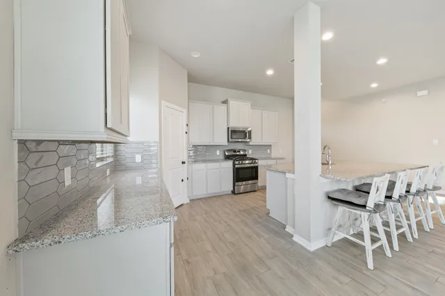 a kitchen with granite countertop stainless steel appliances refrigerator sink dining table and chairs