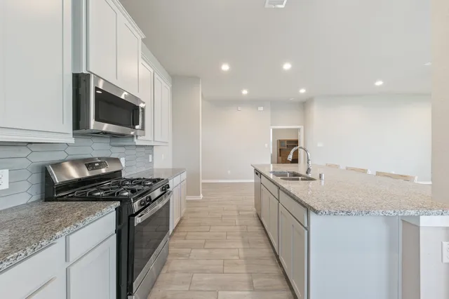 a kitchen with granite countertop sink stove and microwave