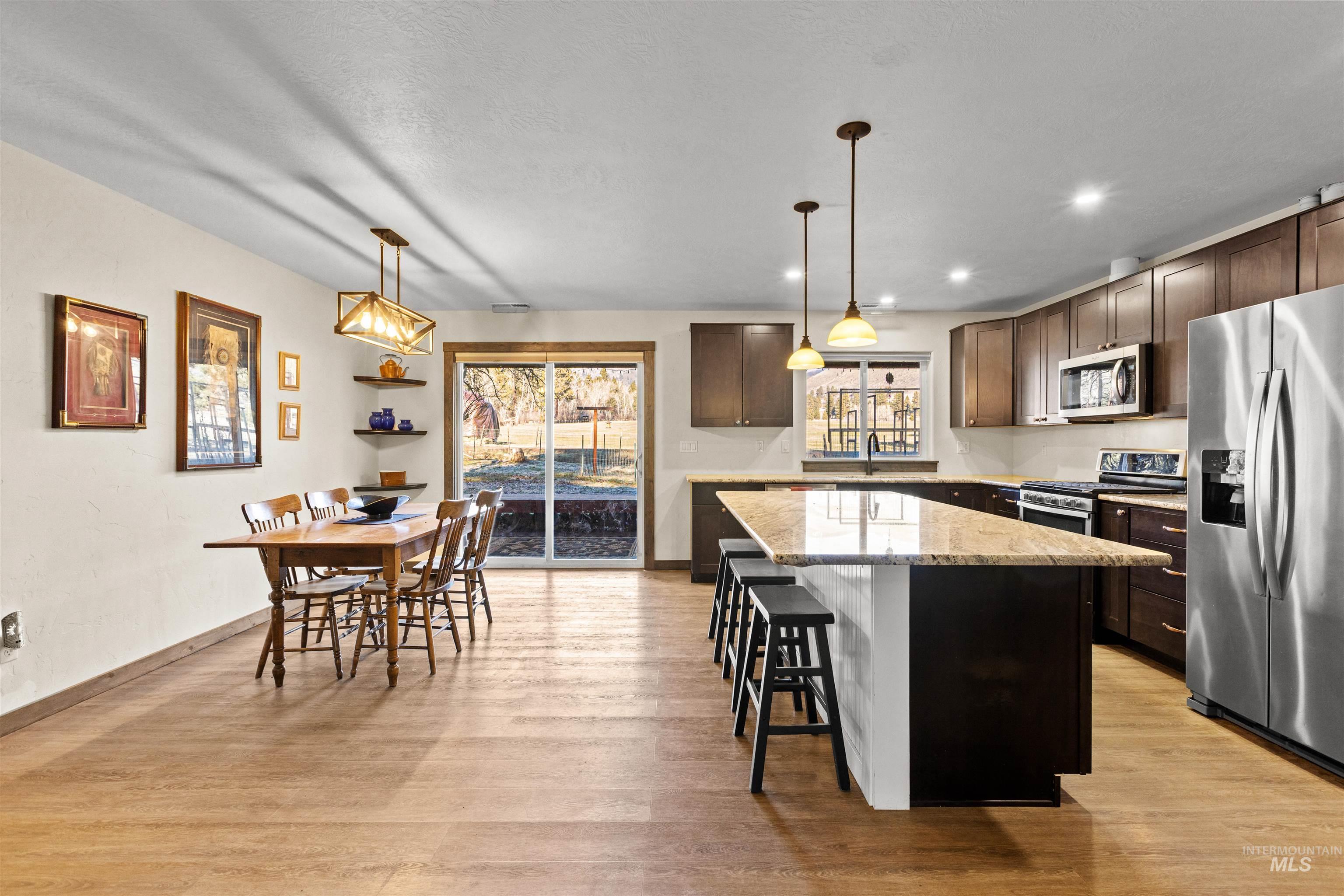 3488 Ward Road Cambridge, ID 83610 - Photo 14 of 49 Kitchen featuring decorative light fixtures, appliances with stainless steel finishes, light stone counters, a center island, and a breakfast bar area