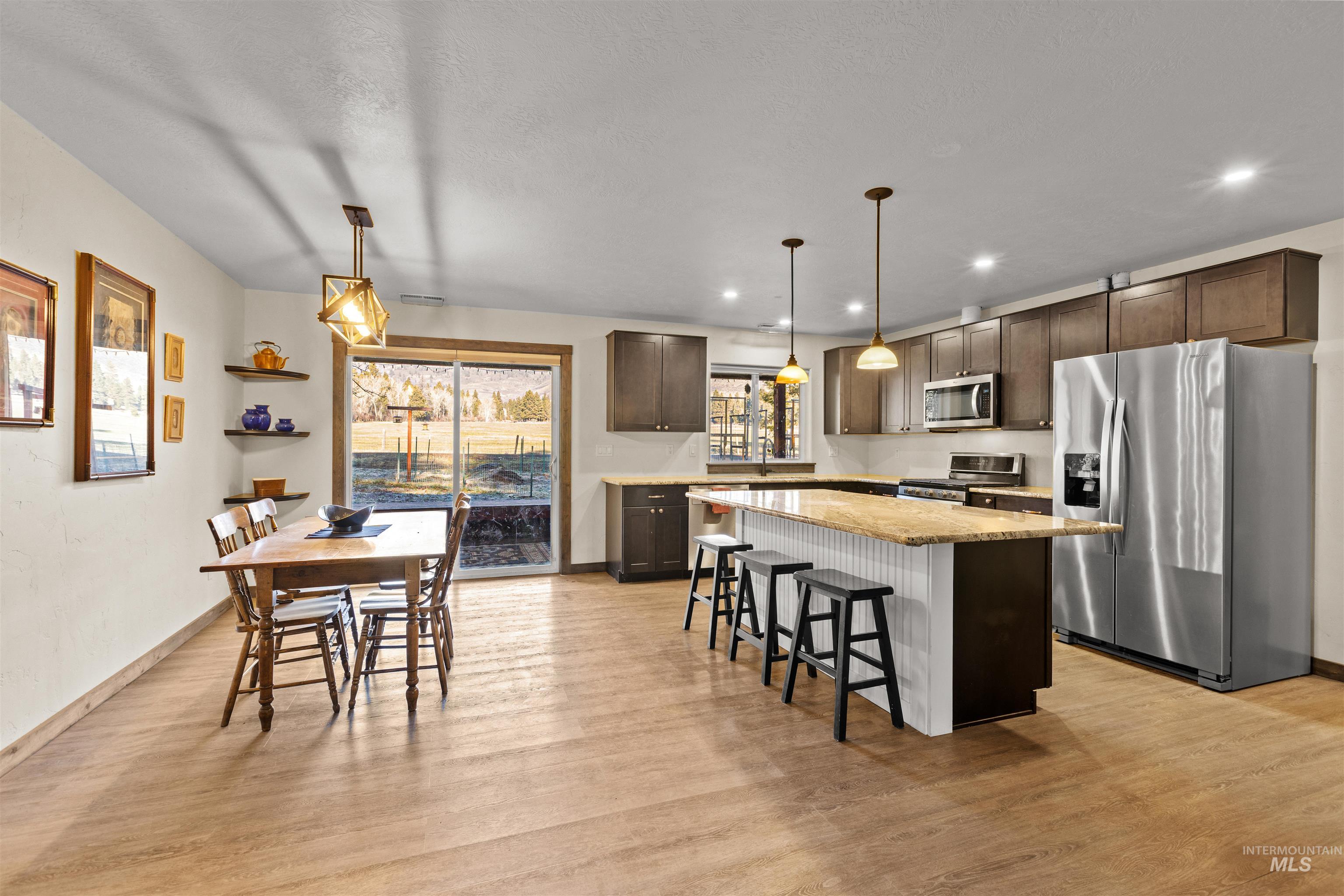 3488 Ward Road Cambridge, ID 83610 - Photo 15 of 49 Kitchen with appliances with stainless steel finishes, dark brown cabinetry, a breakfast bar, decorative light fixtures, and a kitchen island