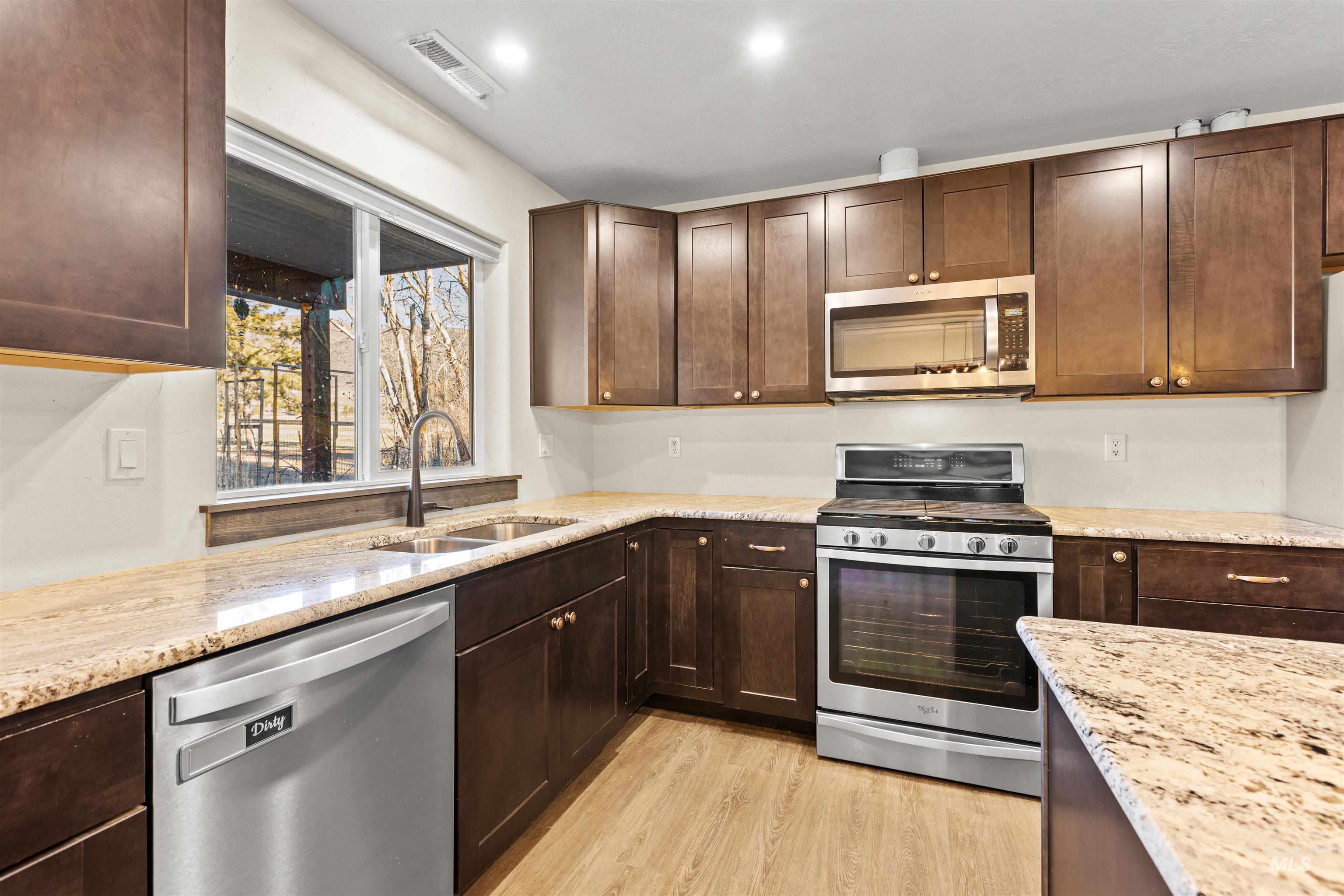 3488 Ward Road Cambridge, ID 83610 - Photo 21 of 49 Kitchen with appliances with stainless steel finishes, dark brown cabinetry, and light stone counters