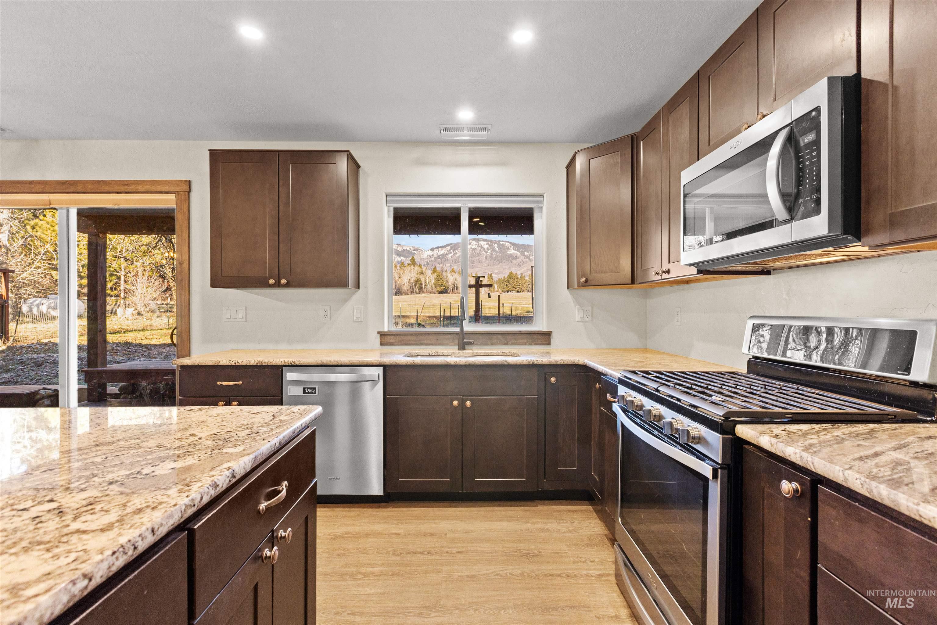 3488 Ward Road Cambridge, ID 83610 - Photo 21 of 49 Kitchen with dark brown cabinetry, stainless steel appliances, light stone counters, light wood-style flooring, and recessed lighting