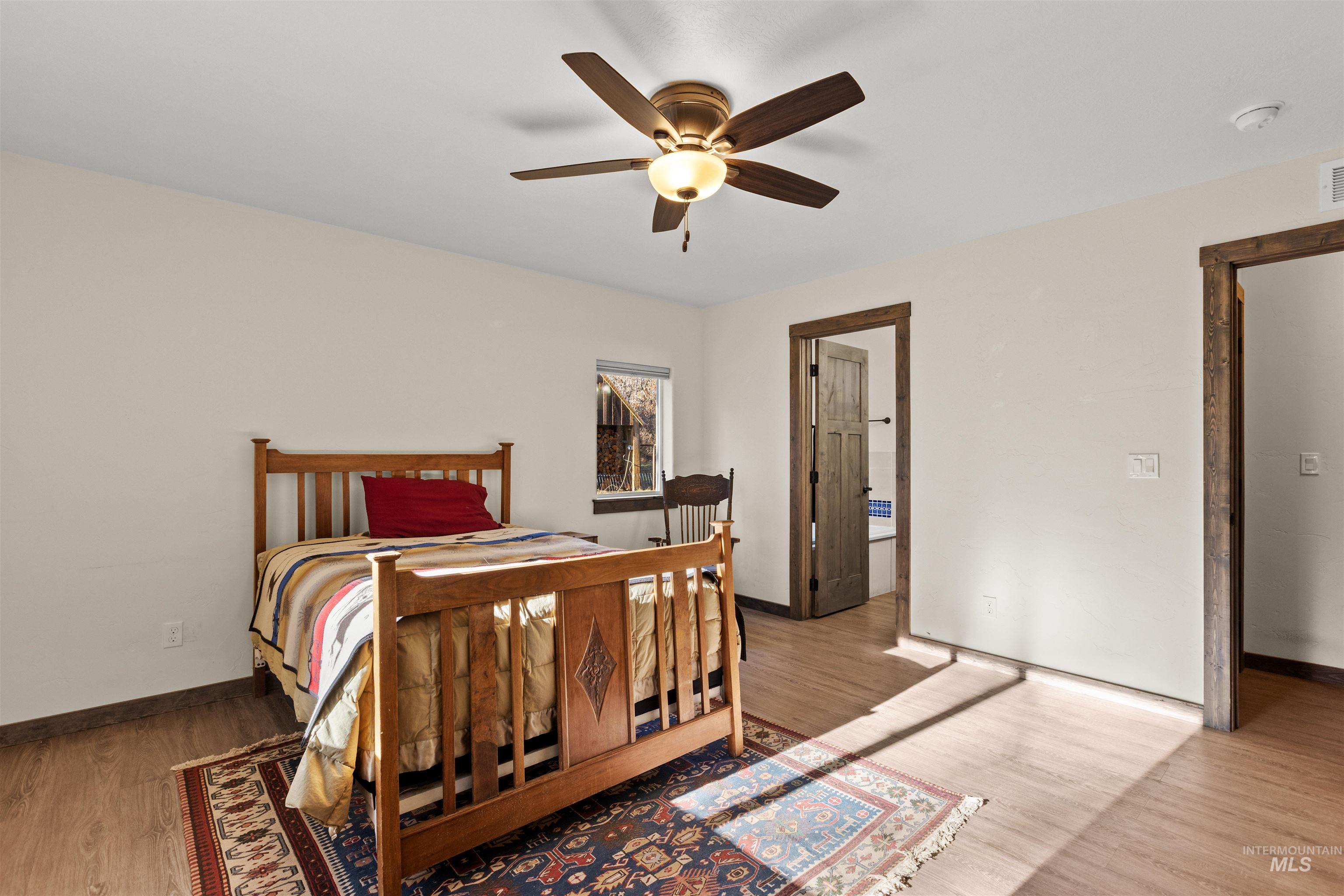 3488 Ward Road Cambridge, ID 83610 - Photo 24 of 49 Bedroom with light wood-type flooring, a ceiling fan, and ensuite bathroom