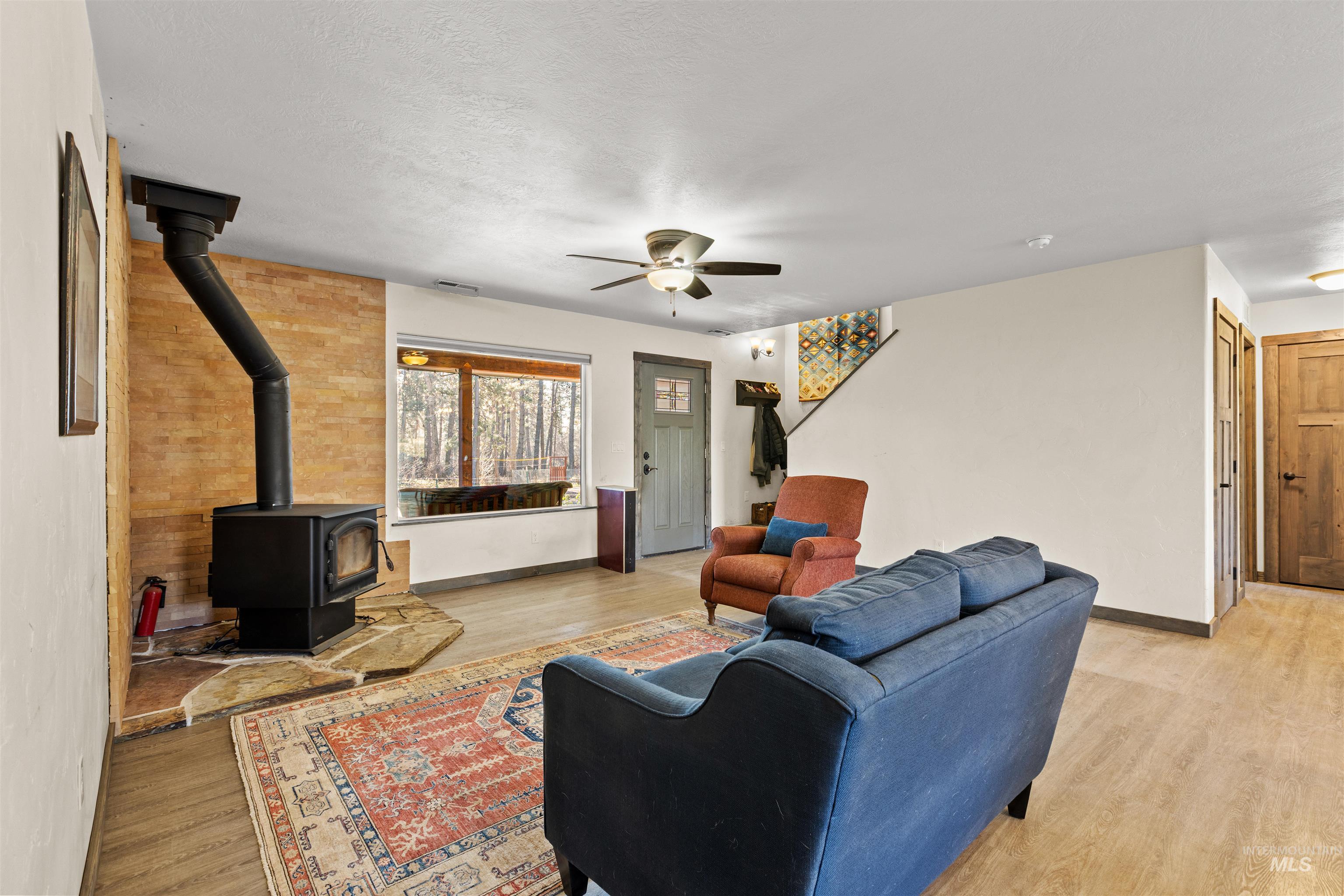 3488 Ward Road Cambridge, ID 83610 - Photo 5 of 49 Living room with a wood stove, light wood-style flooring, and a ceiling fan