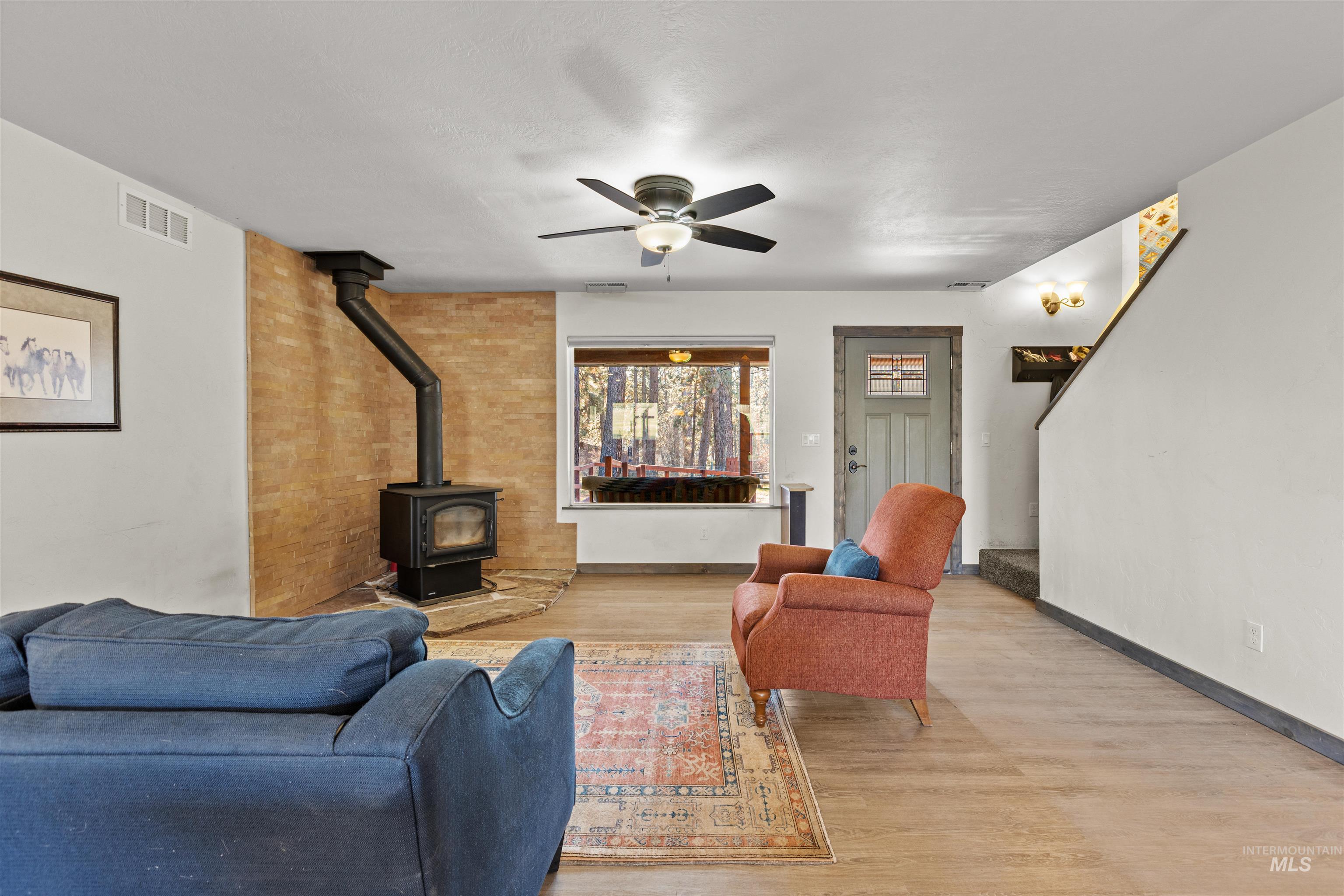3488 Ward Road Cambridge, ID 83610 - Photo 7 of 49 Living room with a wood stove, wood finished floors, a ceiling fan, and stairway