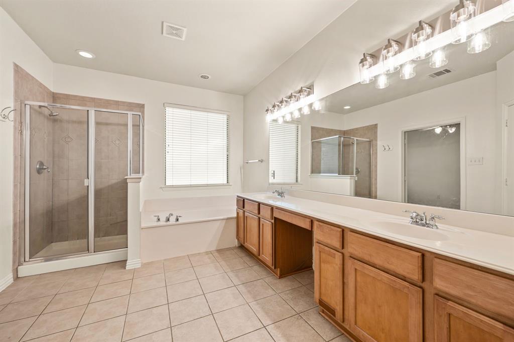 808 Briar Ridge Drive Keller, TX 76248 - Photo 20 of 40 Spacious bathroom featuring twin wood-finish vanities with integrated sinks, a large vanity mirror with overhead lighting, and a glass-enclosed shower with tile surround
