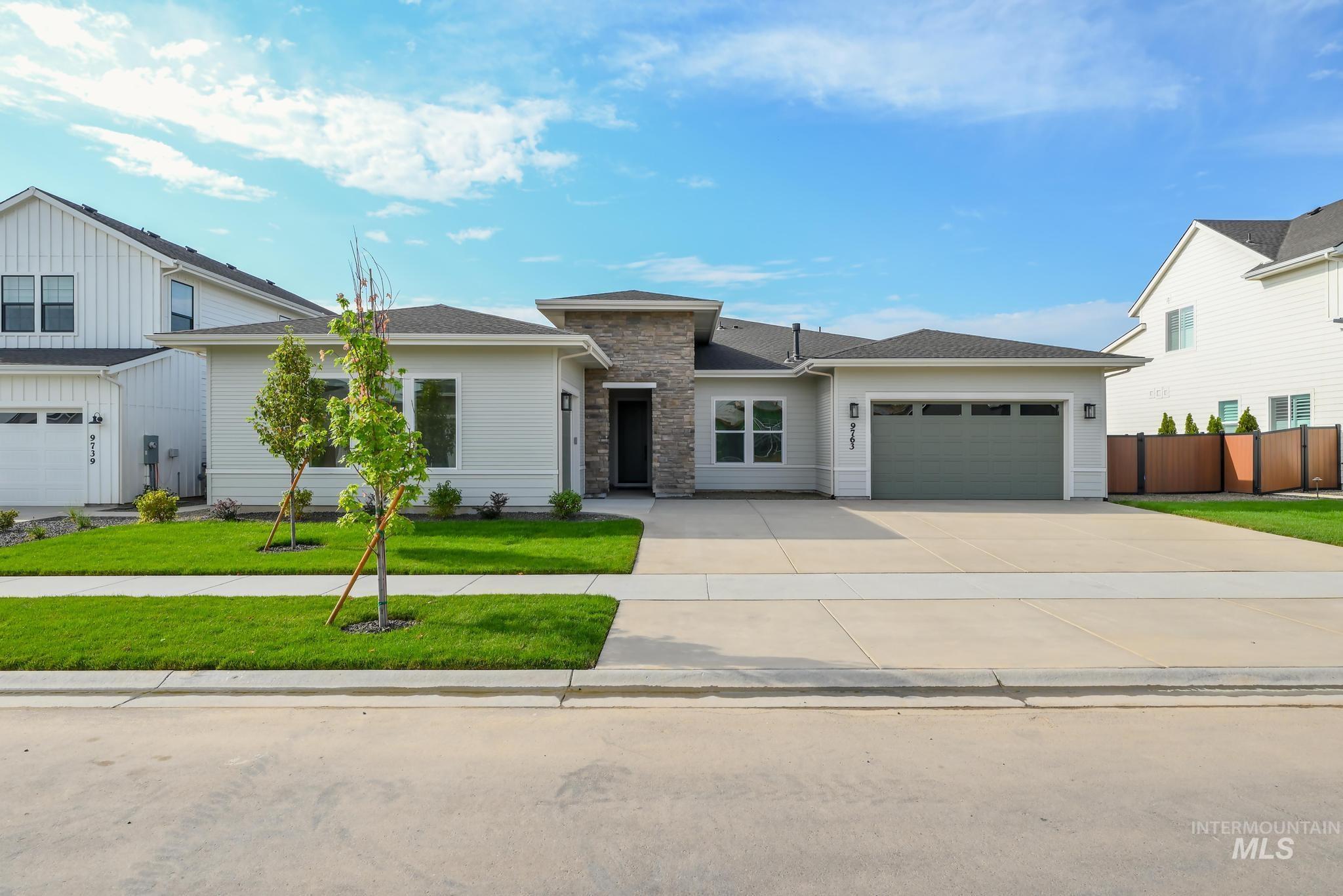 View of front of home with concrete driveway, a garage, and stone siding