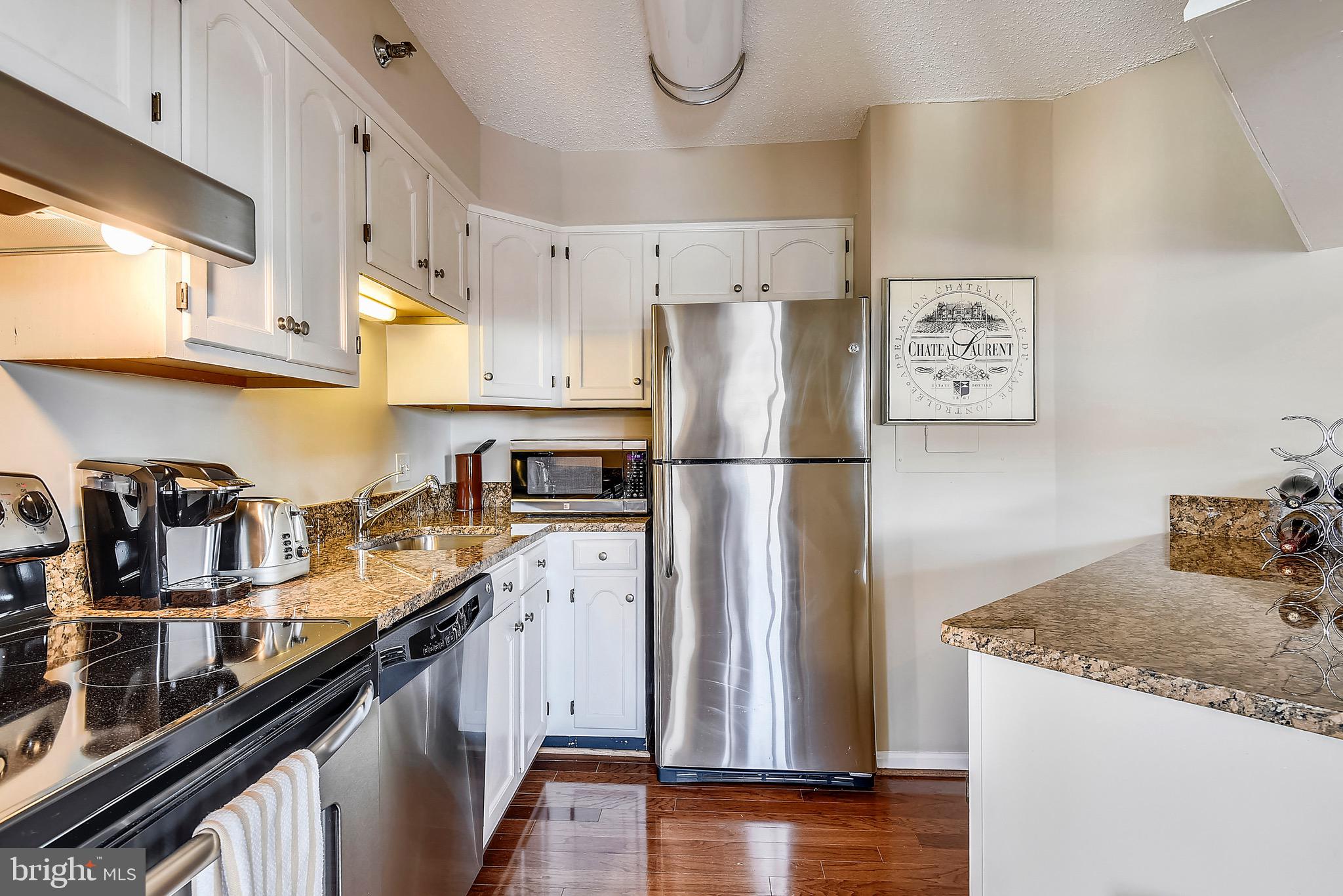 1301 North Courthouse Road, Unit 1503 Arlington, VA 22201 - Photo 3 of 26 a kitchen with granite countertop a refrigerator a sink and wooden floor