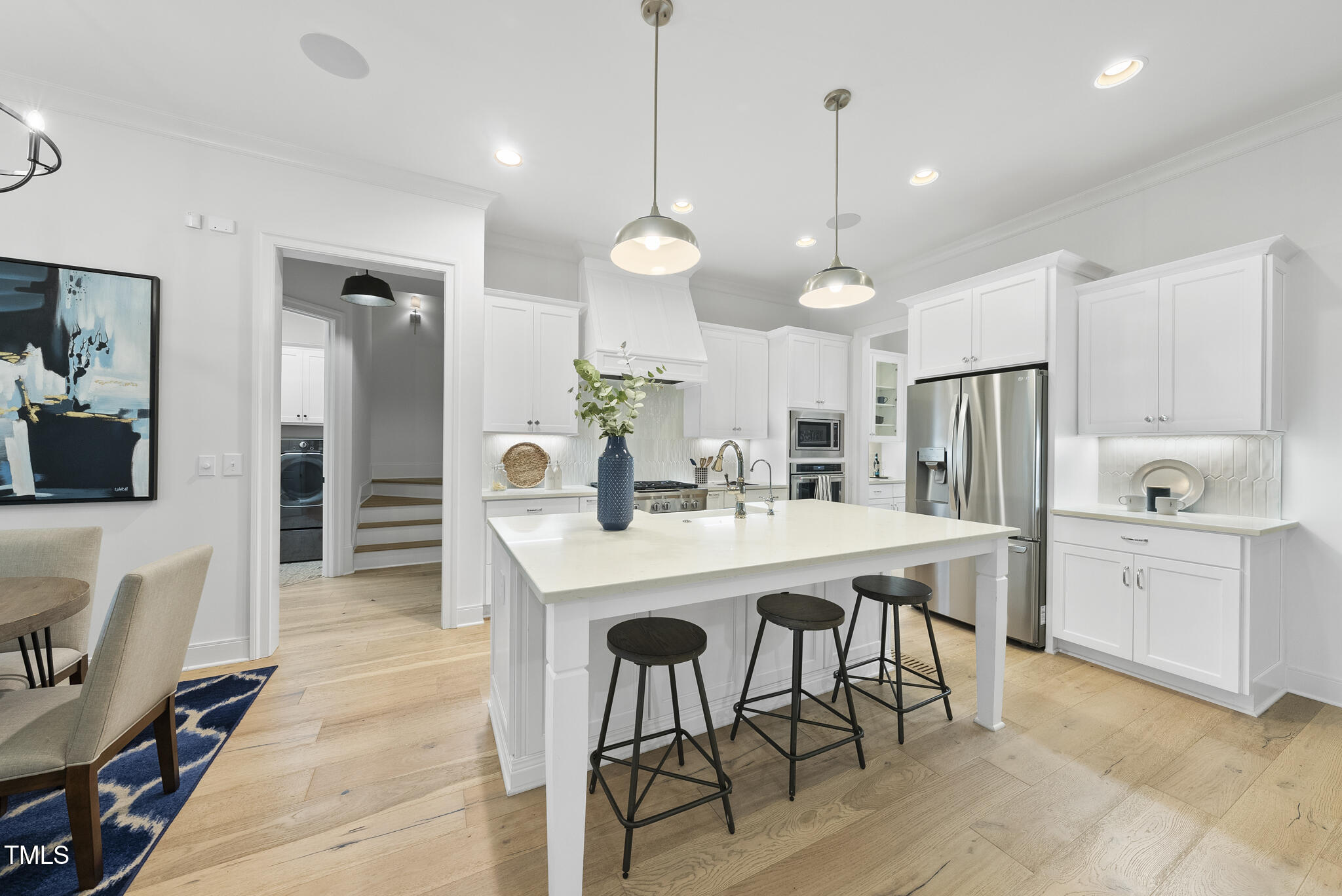 2073 Amalfi Place Apex, NC 27502 - Photo 8 of 40 a kitchen with stainless steel appliances kitchen island granite countertop a dining table chairs and white cabinets