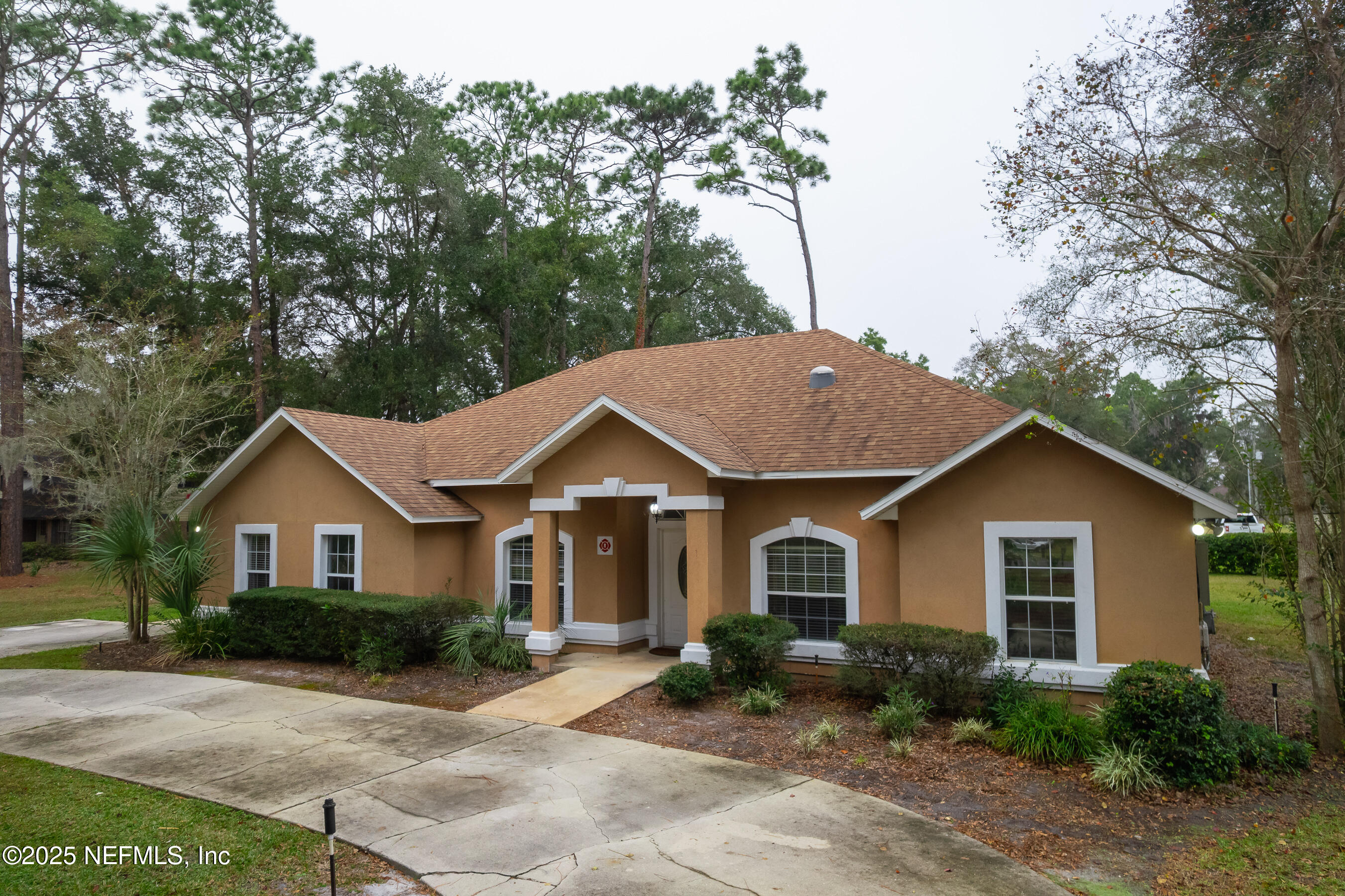 a view of a yard in front of a house with large trees