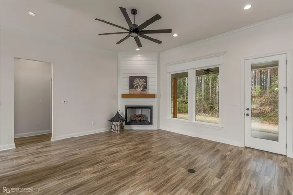 a view of an empty room with a window and wooden floor