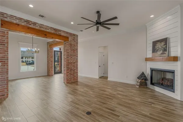 a view of an empty room with wooden floor fireplace and a window
