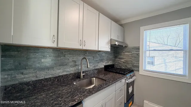 a kitchen with granite countertop a sink and cabinets