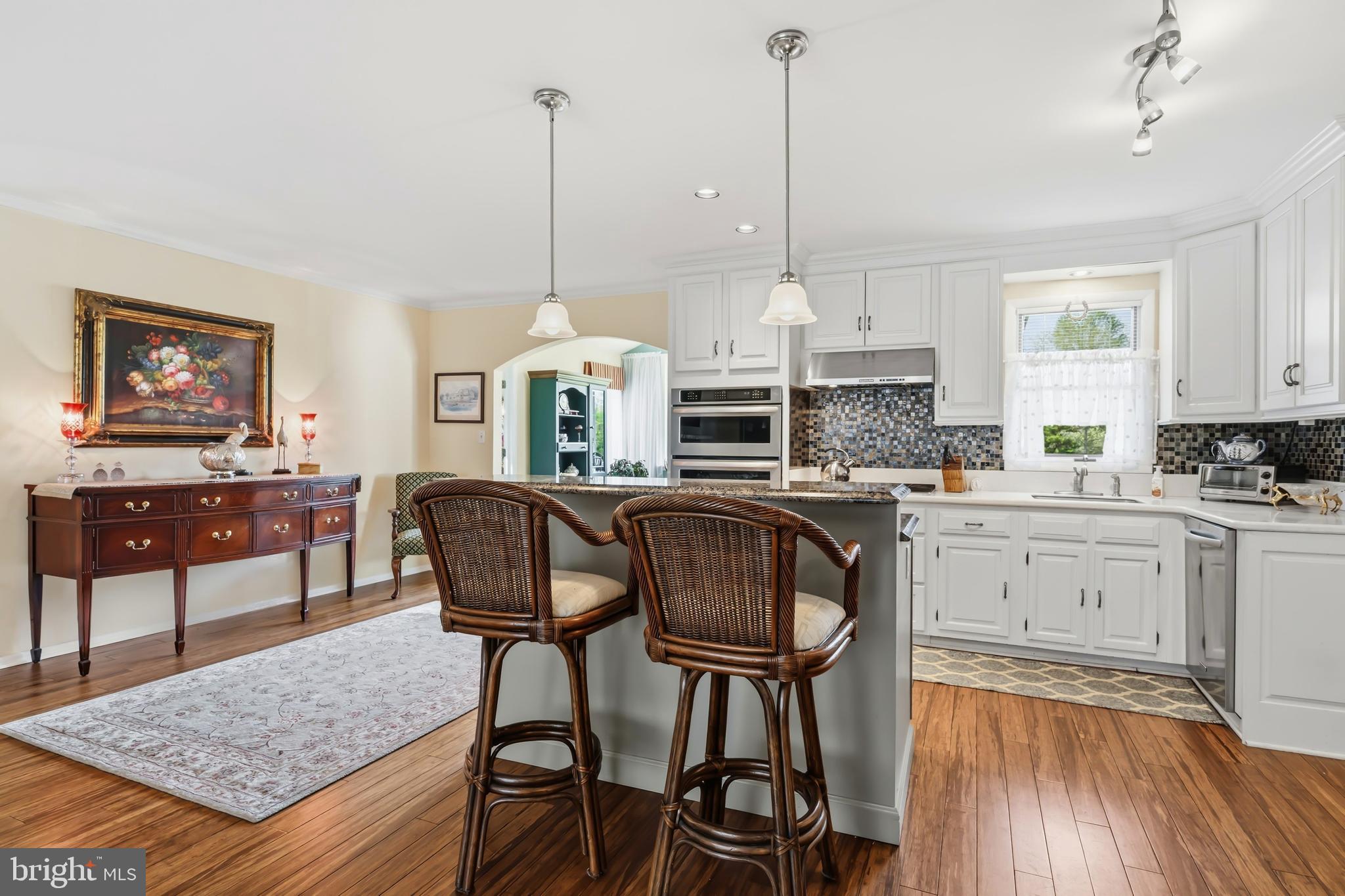 24561 Deepwater Point Drive St. Michaels, MD 21663 - Photo 17 of 50 a kitchen with stainless steel appliances granite countertop a stove top oven a dining table and chairs with wooden floor