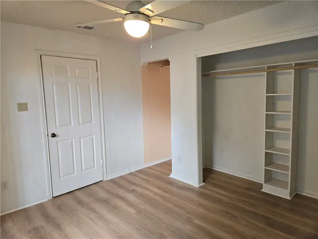an empty room with wooden floor closet and windows