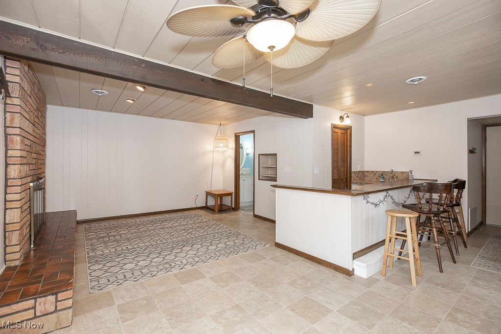2969 Center Road Avon, OH 44011 - Photo 15 of 33 Kitchen featuring a fireplace, a kitchen breakfast bar, ceiling fan, and beam ceiling