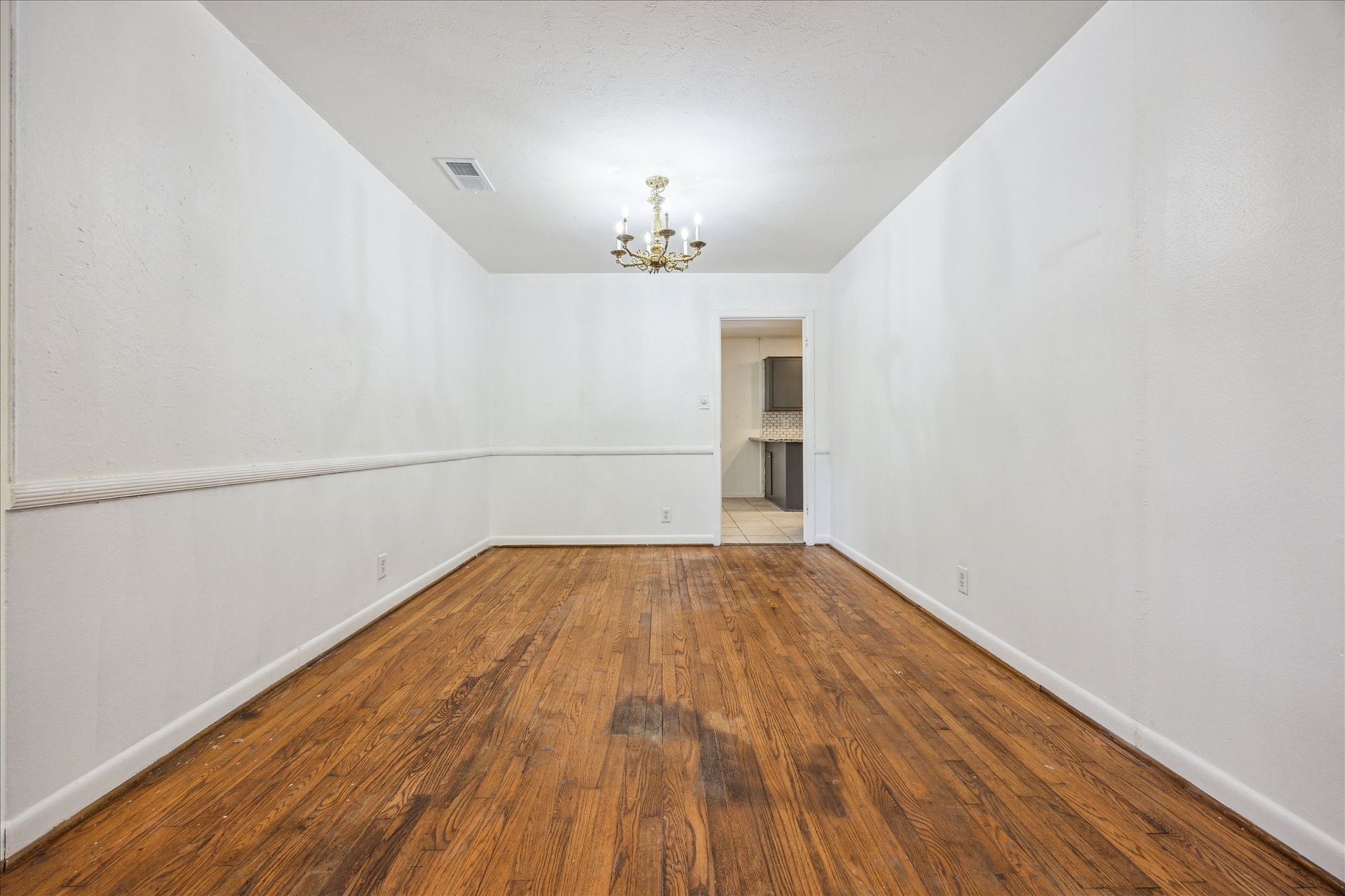 5419 Beechnut Street Houston, TX 77096 - Photo 7 of 28 Dining space with chandelier lighting and wood floors, conveniently connected to the kitchen.