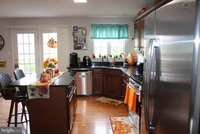 a kitchen with stainless steel appliances granite countertop a stove top oven a dining table and chairs with wooden floor