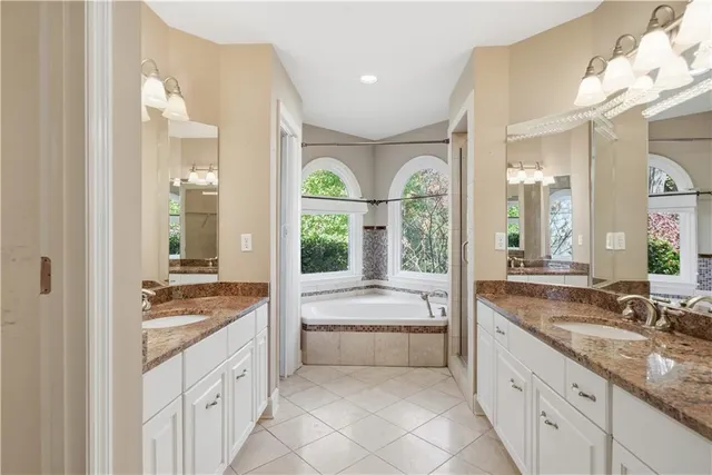 a spacious bathroom with a granite countertop tub mirror and window